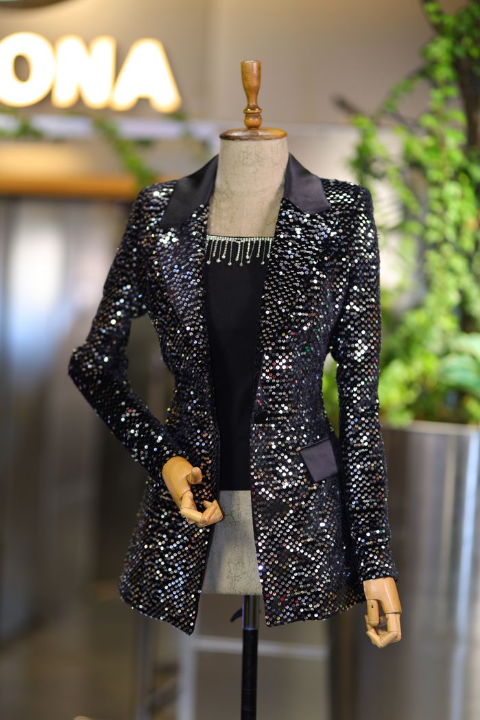 about-us A stylish sequin jacket displayed on a mannequin inside a fashion store.